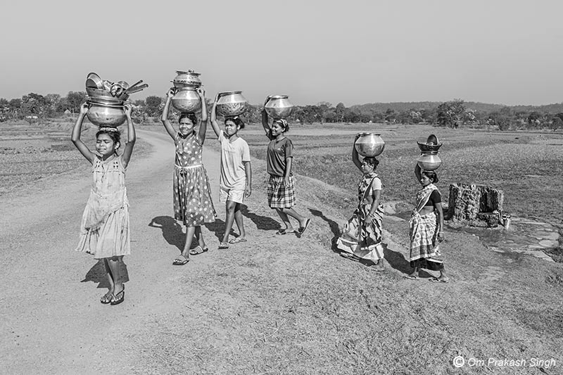 Returning home with drinking water for the day collected from the Kukuru Daarhi in Jiuri village, Jharkhand, India